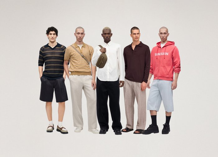 Cinq hommes debout en rang portant des tenues décontractées de printemps, comprenant des shorts, des pantalons, des chemises, un sweat à capuche et un sac bandoulière.