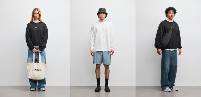 Tre modeller står mod en ensfarvet baggrund iført afslappet streetwear: sort sweatshirt og jeans, hvid langærmet og shorts, sort sweatshirt med crossbody taske.