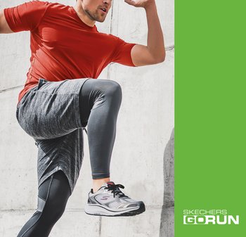 Man in red shirt and gray leggings lifting knee, wearing Skechers GOrun sneakers, against a concrete wall with green branding panel.
