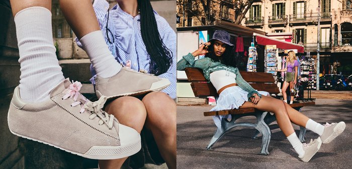 Mujer con zapatillas beige, calcetines blancos, camisa de cuadros y falda sentada en un banco en un mercado al aire libre urbano.