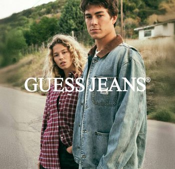 Giacca di jeans con colletto marrone, colore blu e tasche, abbinata a una camicia a quadri rossa con bottoni. Sfondo verde con una strada.