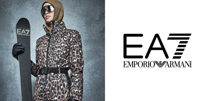 Chaqueta de esquí con estampado de leopardo y cintura con cinturón, combinada con guantes negros y un esquí. El modelo lleva gafas de sol y un pañuelo de punto en la cabeza.