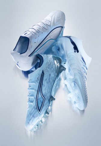Paire de chaussures à crampons blanches et bleu clair avec des logos bleu foncé et des crampons transparents, disposées pour présenter les vues latérale et de la semelle.
