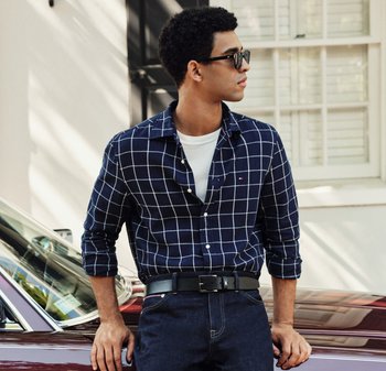 Marineblaue karierte Button-down-Hemd mit hochgekrempelten Ärmeln, über einem weißen T-Shirt getragen, kombiniert mit dunklen Jeans und einem schwarzen Gürtel.