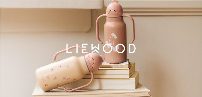 Dos botellas de agua para niños pequeños con asas, una rosa con diseños de corazones sobre libros apilados y otra beige con patrones florales tumbada de lado.