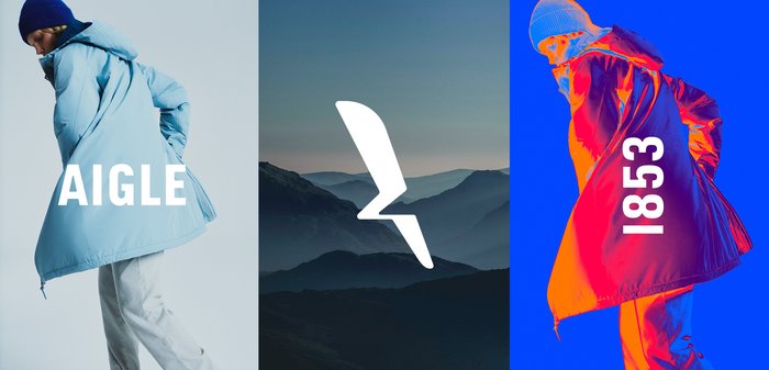 Veste rembourrée bleue avec capuche, présentant une texture brillante et une fermeture éclair sur le côté. Les éléments centraux incluent un graphique de montagne et un texte en gras : "AIGLE" et "1853."