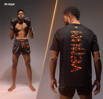 Svart t-skjorte med oransje grafisk tekst på baksiden, kombinert med svarte shorts med oransje mønster, modell posert med boksehansker.