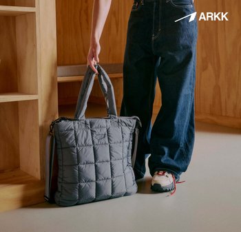 Grå quiltet totebag med doble håndtak og en justerbar skulderrem, med glidelås og polstret tekstur.