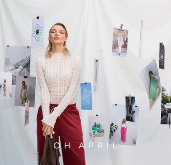 Sheer, long-sleeve lace top with ruffled cuffs, paired with burgundy sweatpants. Background features hanging fashion photos on white fabric.