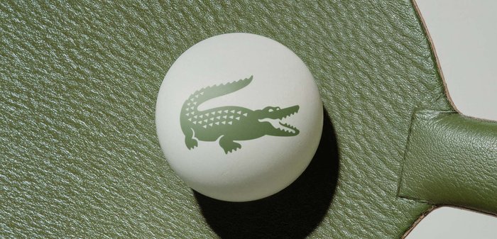 Balle de ping-pong blanche avec logo de crocodile vert sur la poignée et la surface texturées de la raquette verte.
