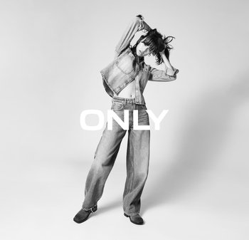 Lichtgewassen denimjack met rafelige zoom en zakdetails, gecombineerd met losse denimjeans. Model draagt zwarte hakken.