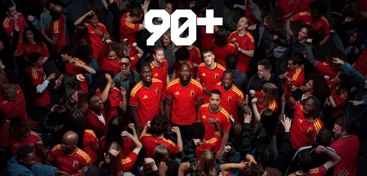 Menigte mensen die rode en gele Belgische voetbalshirts dragen, vieren met tekst "90+" erboven, wat verlengde speeltijd aangeeft.
