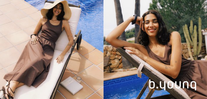 Frau in braunem Kleid und breitkrempigem Sonnenhut entspannt sich auf einer Pool-Liege neben einem Buch und einem Glas auf dem gefliesten Deck.