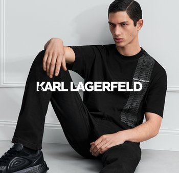 Camiseta de algodón negra con un diseño de rayas verticales texturizadas, que presenta el nombre de la marca "Karl Lagerfeld" en blanco contrastante. Modelo sentado.