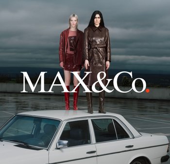 Dwie kobiety stoją na dachu białego samochodu na deszczowym parkingu, ubrane w skórzane płaszcze i botki, pod pochmurnym niebem z napisem "MAX&Co.".