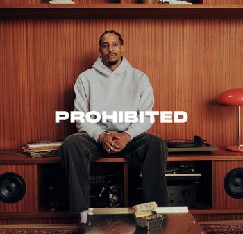 Gray hoodie with a logo, green corduroy pants, sitting on a wooden shelf with a vinyl player, records, and a red lamp. Bold "PROHIBITED" text overlay.