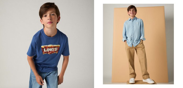 Pojke som bär en blå Levi's t-shirt med en grafisk logotyp och ljusblå jeans, lutande lite framåt mot en enkel bakgrund.