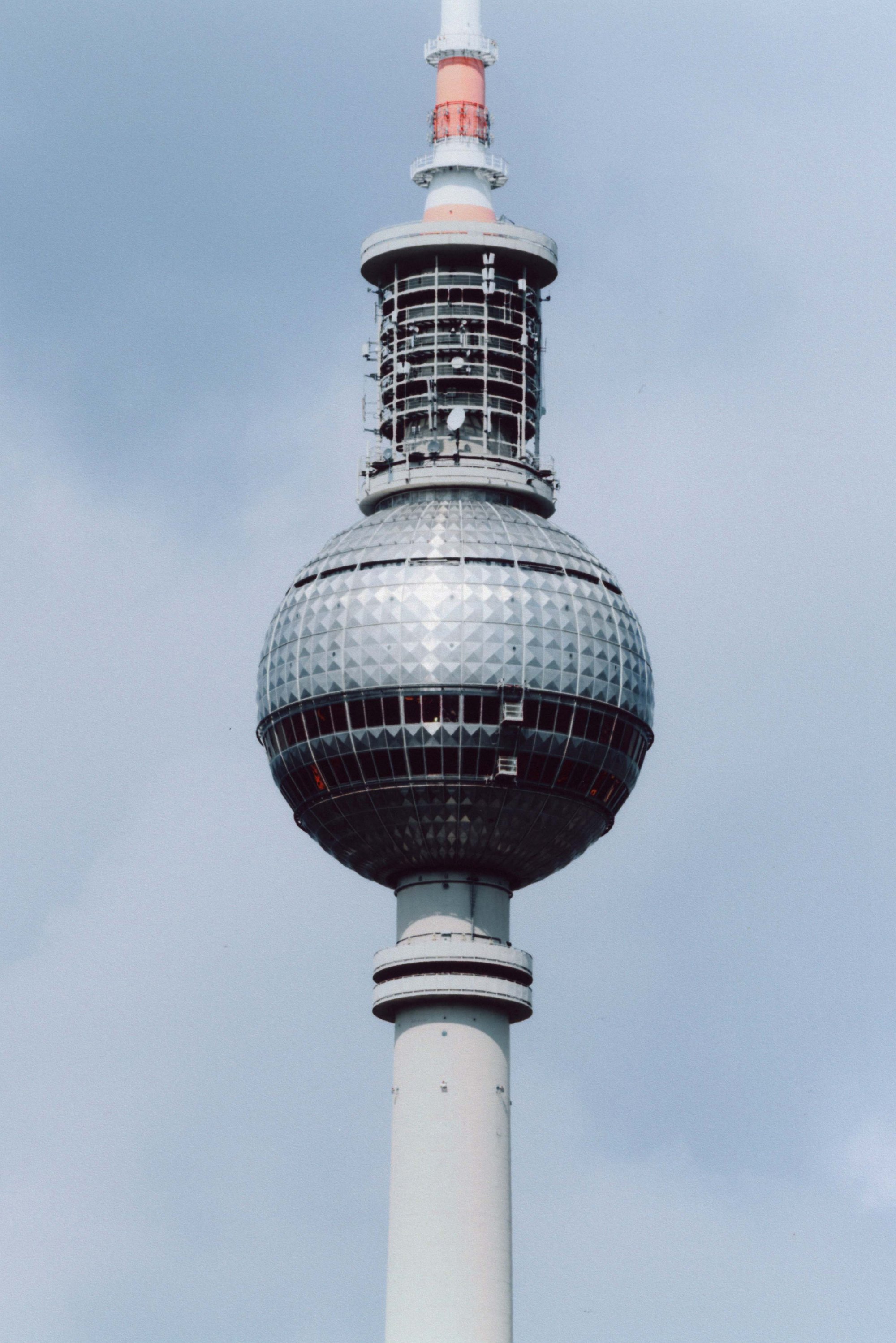 Television tower with a spherical design, featuring a silver patterned surface, a cylindrical white base, and an upper section accented with orange.
