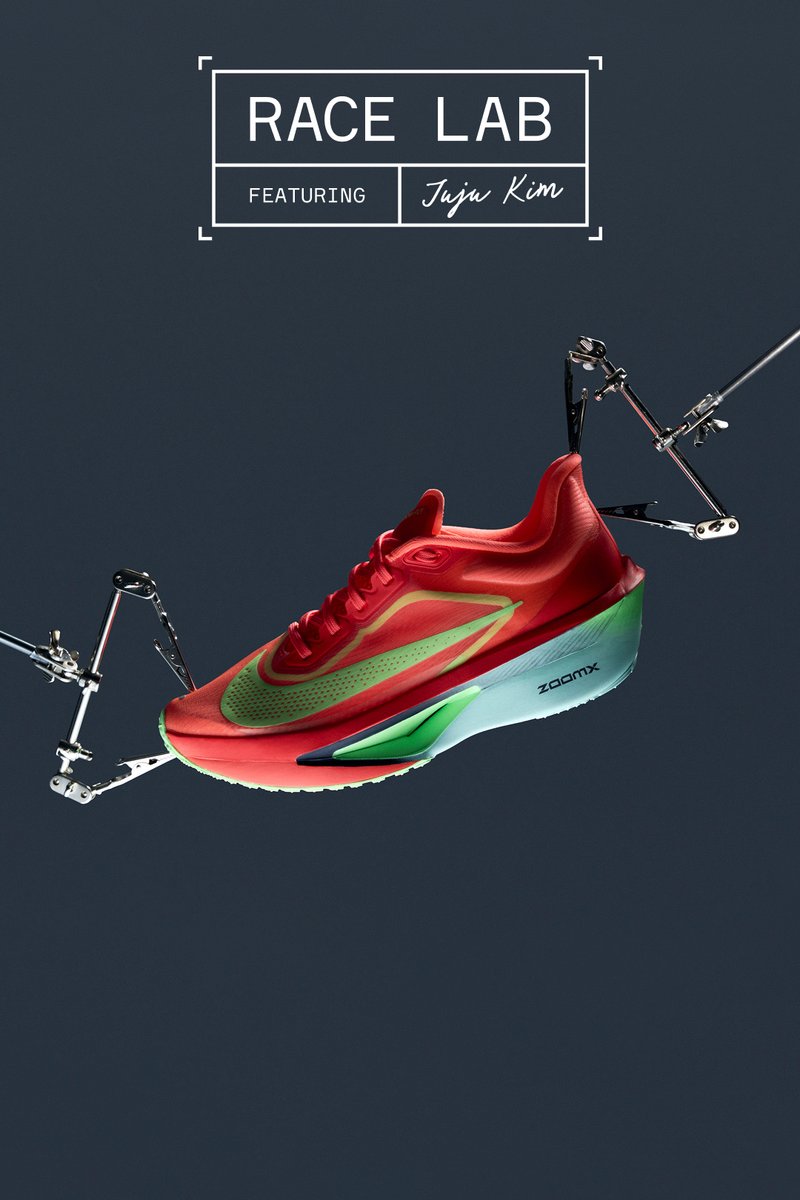 Red running shoe with green accents, featuring a textured upper and a large zoom air cushion sole. Suspended with mechanical arms against a dark background.