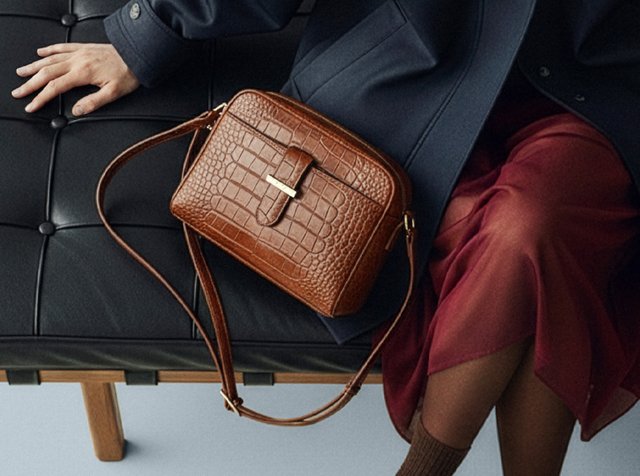 Brun krokodilmönstrad läderväska med rektangulär form, guldfärgade detaljer och avtagbar axelrem. Slät textur.