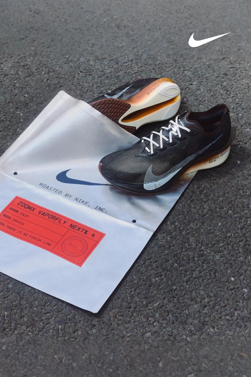 Black Nike ZoomX Vaporfly NEXT% 4 running shoes with white accents, positioned on a white bag adorned with red text and logo. Textured outsole is visible.