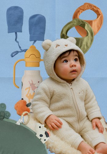 Cremfarbener Fleece-Overall mit Bärenohren, daneben eine gemusterte Wasserflasche, farbige Lätzchen und strukturierte Spielzeuge auf einem blauen Hintergrund.