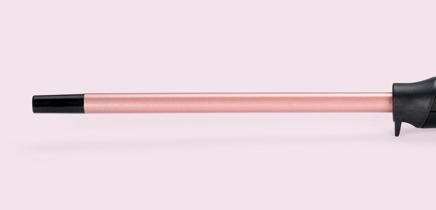 Roze metalen wandelstoksteel met een zwart rubberen punt en ergonomisch zwart handvat op een lichtroze achtergrond.