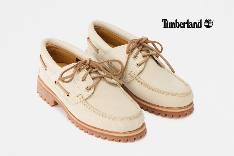 Beige leather Timberland boat shoes with brown laces and rugged rubber soles, positioned side by side on a white background.