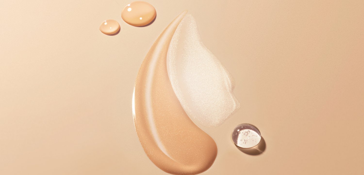 Glatt verlaufende Muster aus beigen und schimmernden Creme-Texturen mit drei flüssigen Tropfen auf einem weichen beigen Hintergrund.