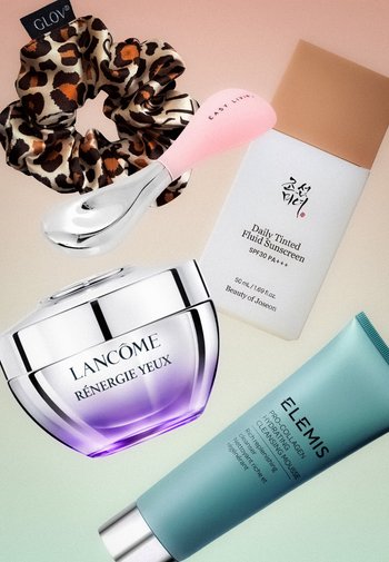 Haargummi mit Leopardenmuster, rosa Gesichtsmassagegerät, getönte Sonnencreme, Lancôme Augencremeglas und Elemis feuchtigkeitsspendender Reinigungsschaum in der Tube.