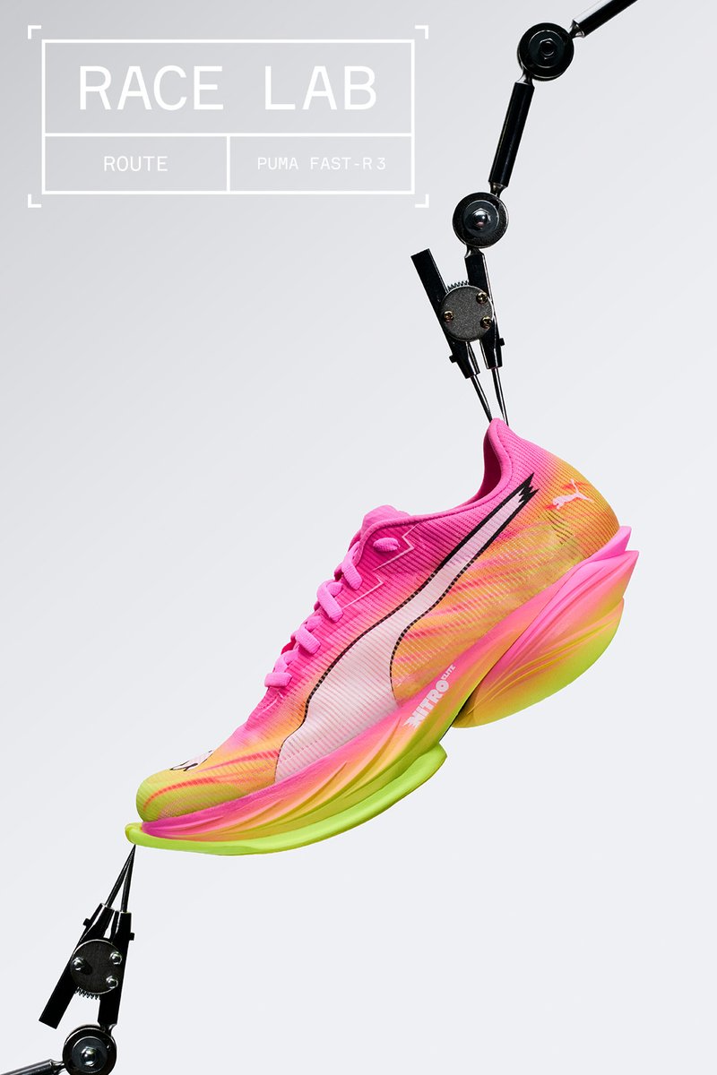 Chaussure de course Puma rose vif et jaune tenue par des bras mécaniques sur un fond uni avec le texte Race Lab.
