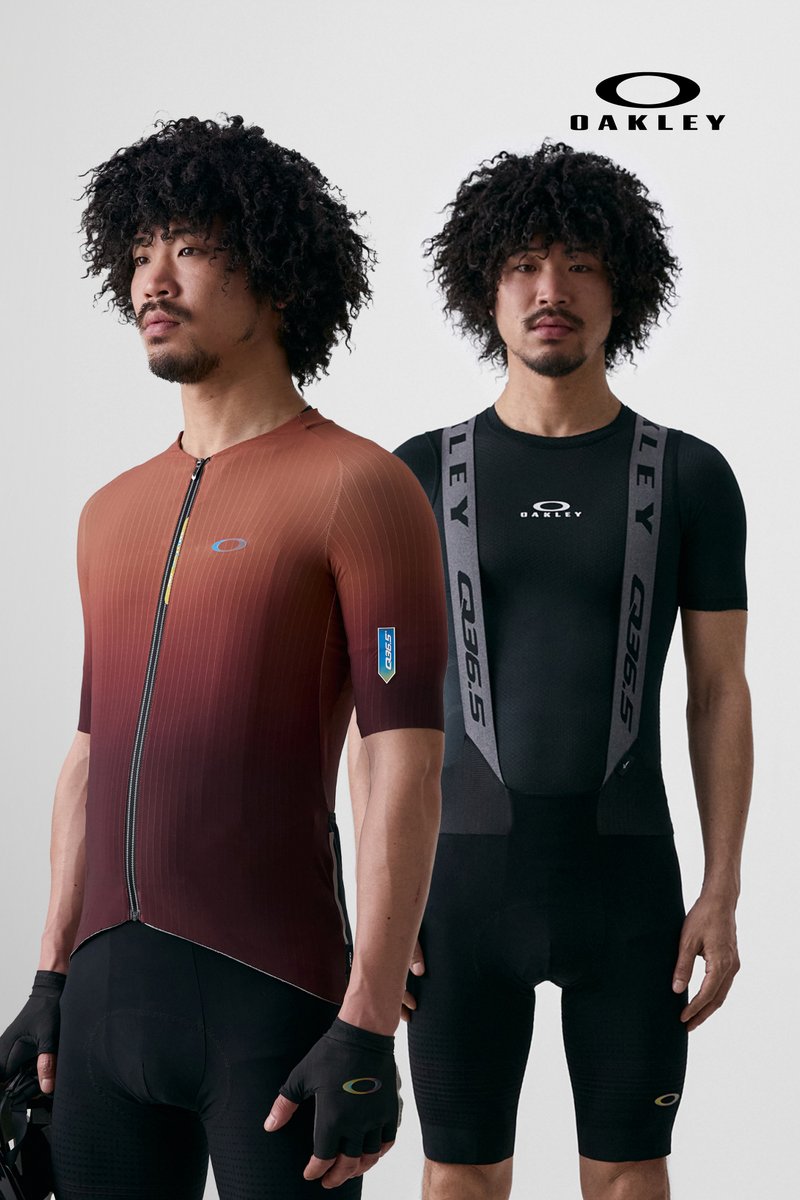 Two male models with curly hair showcase cycling outfits: one in a brown gradient top, the other in a black bib shorts. Both wear gloves.