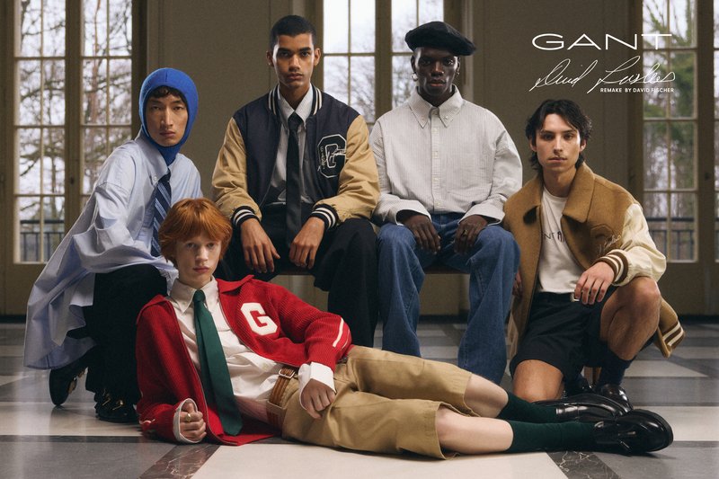 Fem modeller poserar i ett svagt upplyst rum och visar upp olika modes styles. I förgrunden finns en sittande modell i en röd cardigan och khakishorts.