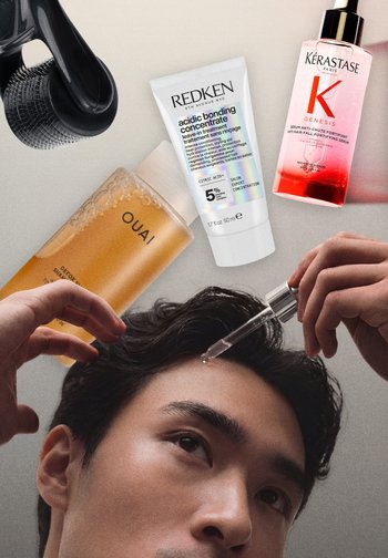 Mand påfører en dråbe serum på panden, med en hårbørste og tre hårplejeprodukter—Redken, Kérastase og OUAI—placeret over hovedet.