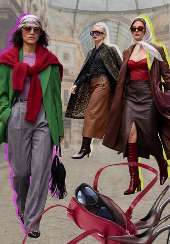 Drie stijlvolle vrouwen in oversized jassen, zonnebrillen, leren rokken en laarzen lopen in een glazen koepelarchitectuur.