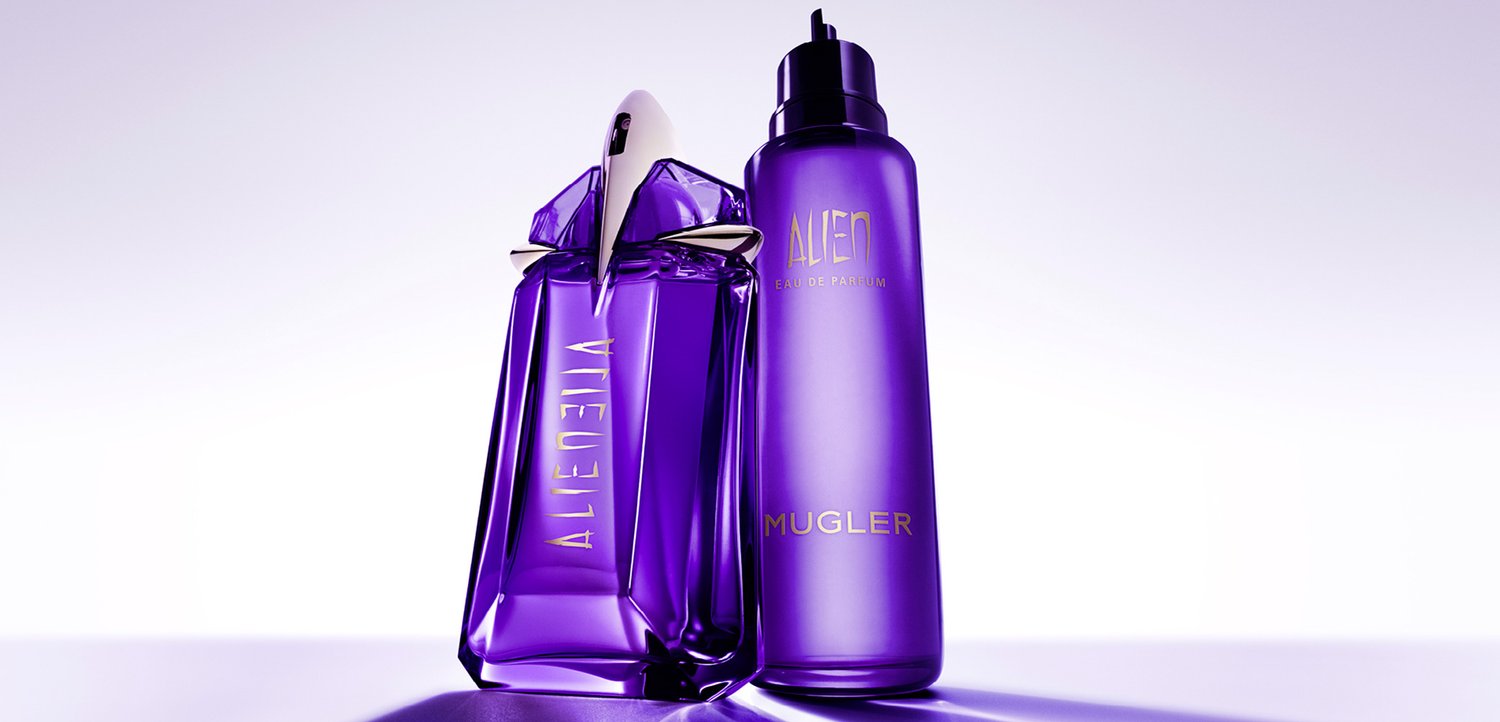 Lilla glasparfume flaske med en stjernesformet låg og en matchende sprayflaske. Begge har guldtryk. Glat, skinnende overflade.