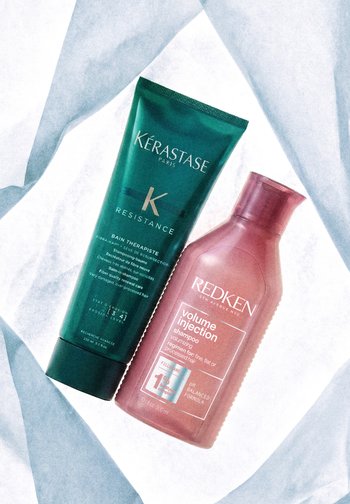 Butelki szamponu Kérastase Resistance Bain Thérapiste i szamponu Redken Volume Injection na białym tle z tkaniny.