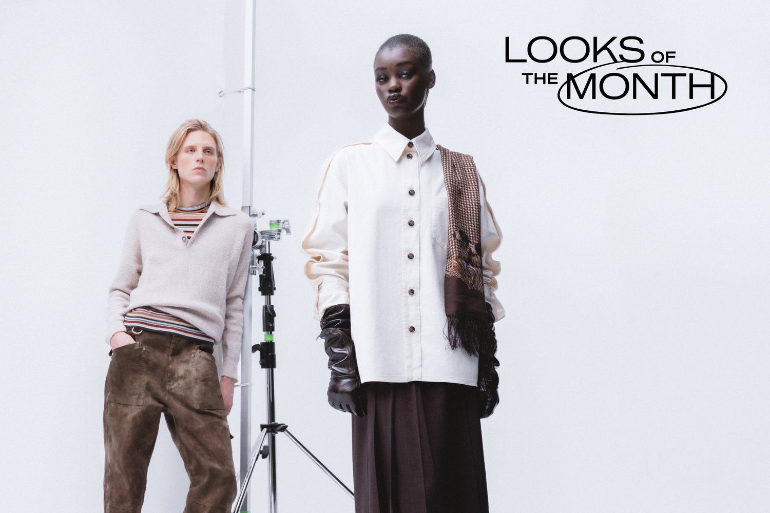 Dos modelos posan en un estudio minimalista. Uno lleva una camiseta oversized color crema y guantes negros, mientras que el otro luce un suéter acogedor y pantalones marrones.