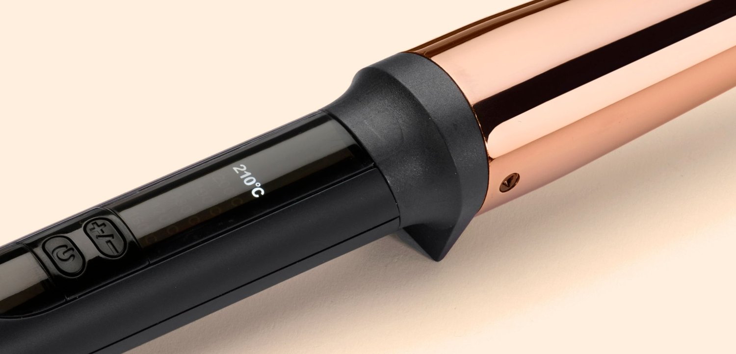Nahaufnahme eines schwarzen und roségoldenen Lockeneisens mit Steuerungstasten und einem digitalen Display, das 210 Grad Celsius anzeigt.