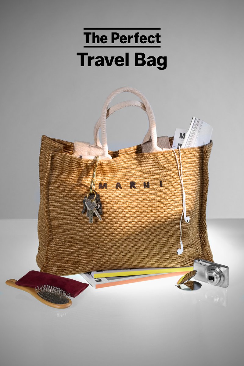 A large woven bag with handles displays keys, a hairbrush, a camera, and papers, emphasizing travel essentials against a neutral backdrop.