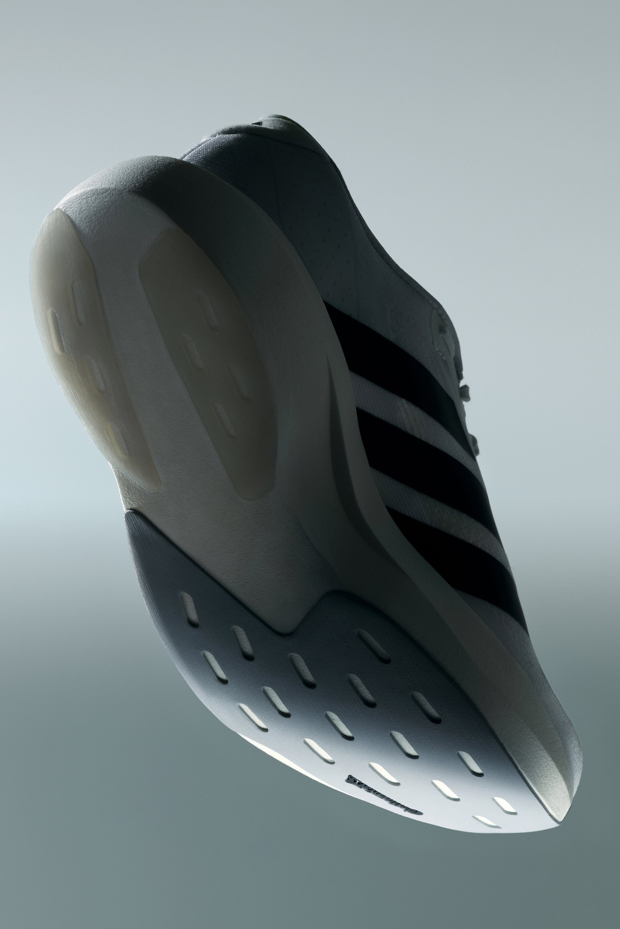 Zapatilla deportiva blanca con tres rayas negras, parte superior de textura suave, cuello acolchado y una suela de goma gruesa y texturizada con patrones de ventilación.