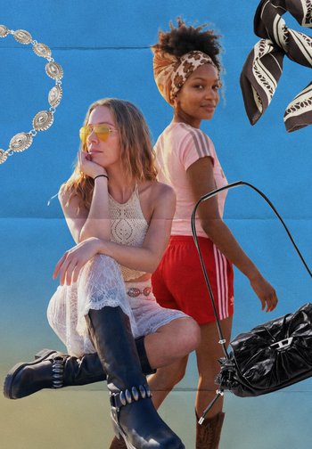 Deux femmes posant devant un fond bleu ; l'une assise en robe blanche en dentelle et bottes, l'autre debout en chemise rose, short rouge et foulard.