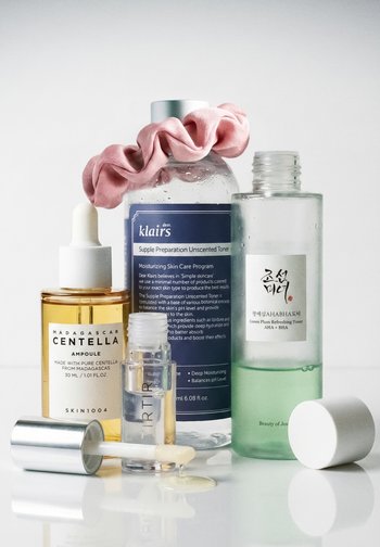 Butelki do pielęgnacji skóry zawierają ampułkę Centella z Madagaskaru z pipetą, bezzapachowy tonik Klairs z różową gumką do włosów oraz orzeźwiający tonik z Zielonej Śliwki.