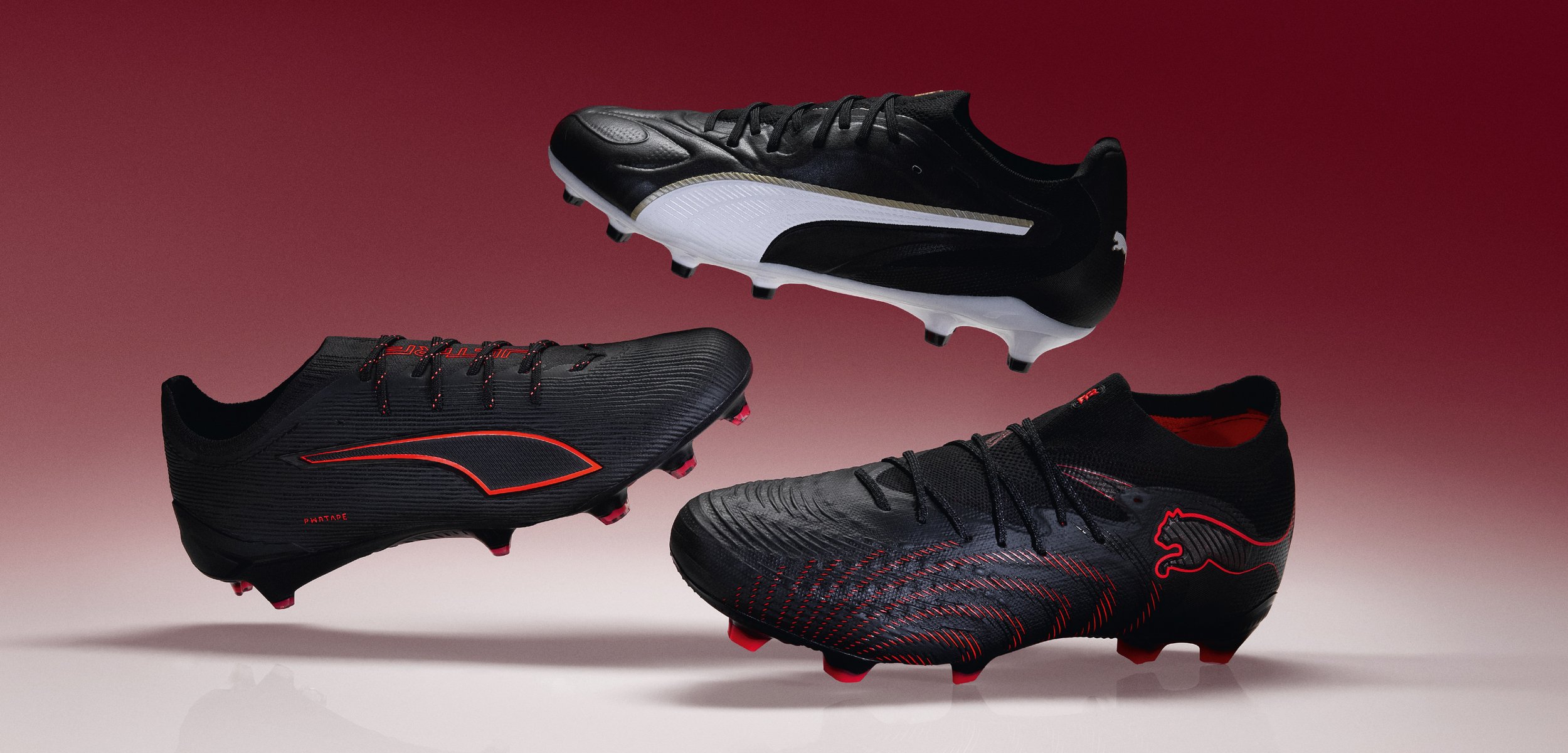 Drie zwarte voetbalschoenen met rode en witte details zweven tegen een rood verloopachtergrond.