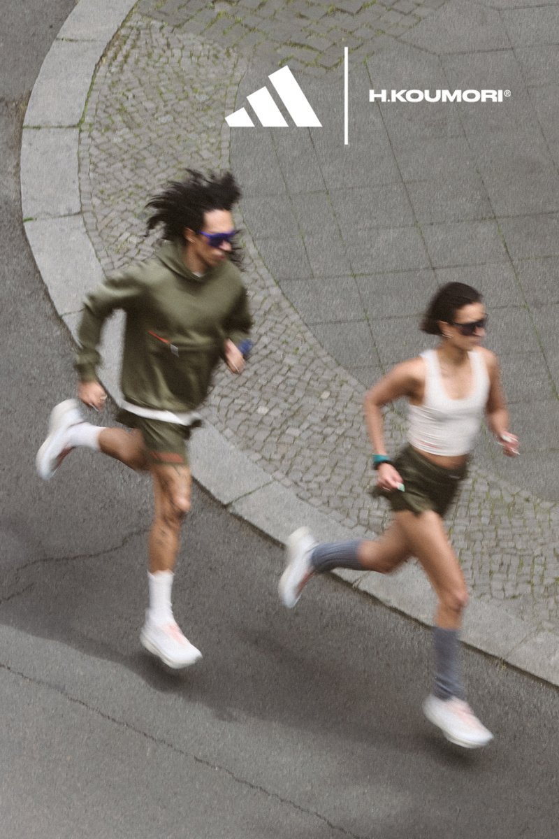 Two runners, a man and a woman, sprint on a cobblestone path. Both wear athletic attire and sunglasses. Branding visible above them.