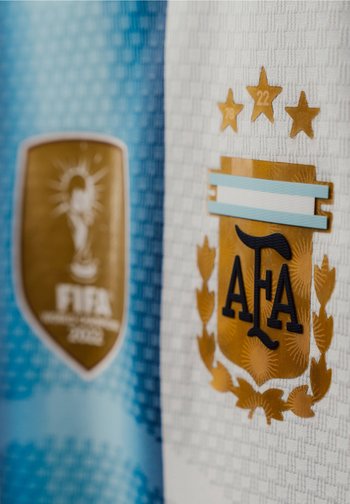 Logos de l’équipe nationale de football d’Argentine sur des maillots texturés bleus et blancs avec trois étoiles d’or et un badge de vainqueur de la Coupe du Monde FIFA 2022.