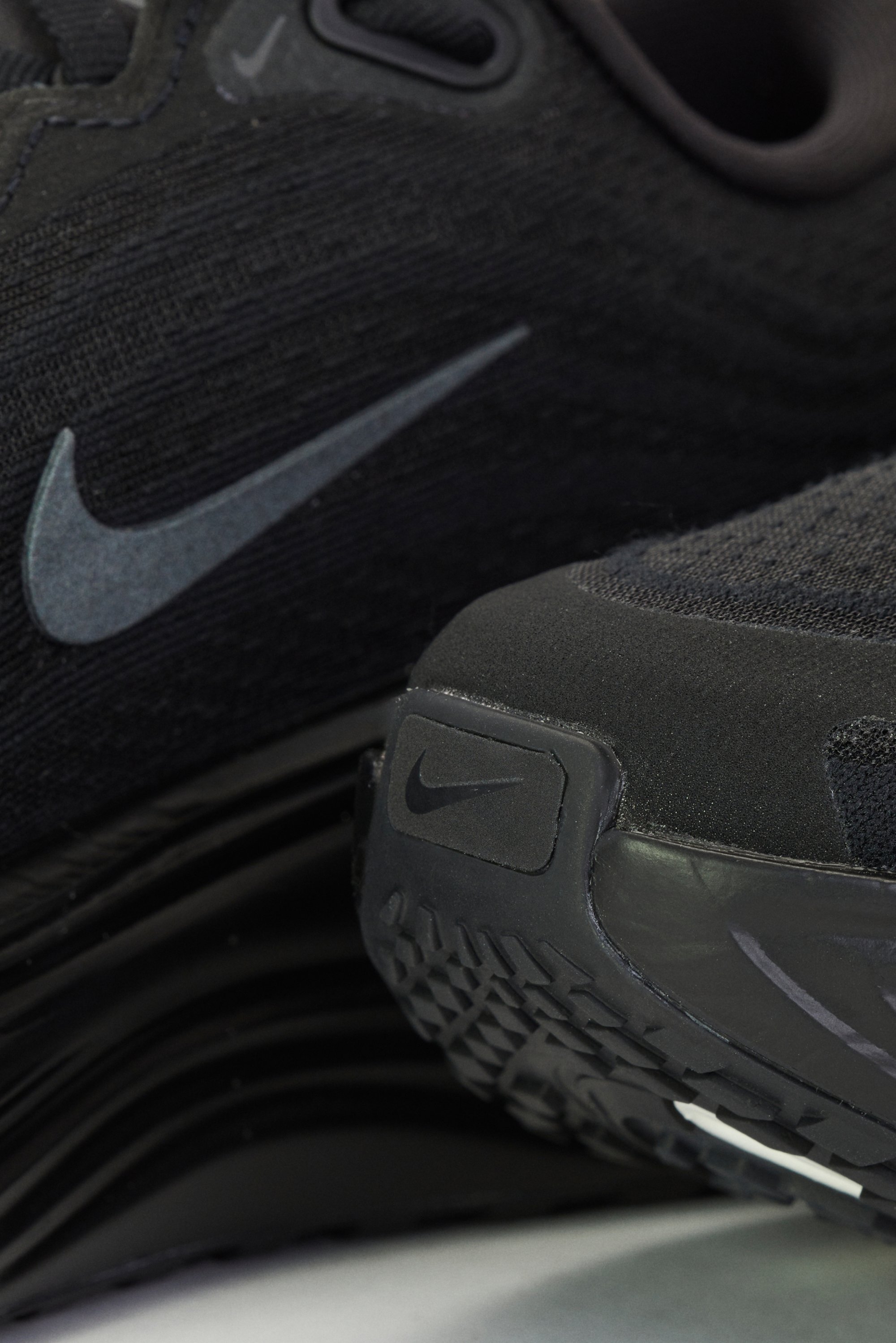 Zwarte sport schoenen met een gestructureerde bovenkant van stof, voorzien van een opvallende grijze Nike swoosh. De zool heeft een patroon voor grip en het merkembleem.