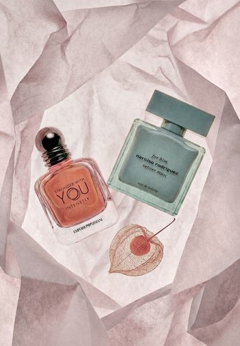 Dos frascos de perfume, Emporio Armani Stronger With You Intensely y Narciso Rodriguez for Him Vetiver Musc, sobre un papel arrugado de color rosa pálido.