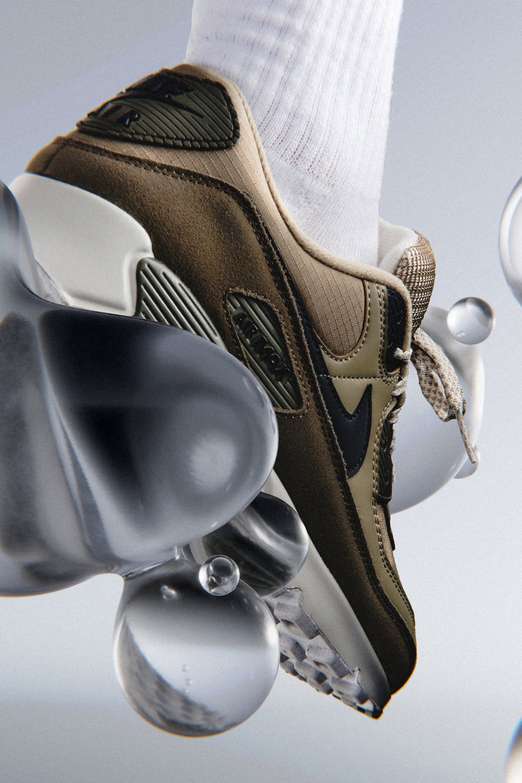 Close-up van een beige en olijfgroene sneaker met een gestructureerd oppervlak, gepositioneerd boven doorzichtige, bolvormige objecten tegen een zachte achtergrond.