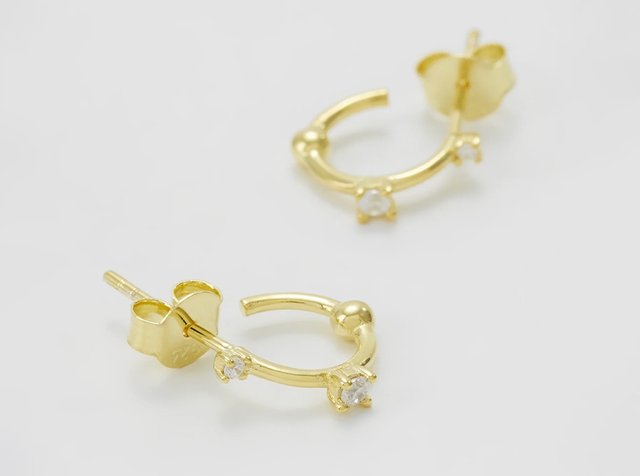 Small gold hoop earrings with two small clear gemstones on each, shown on a white background.